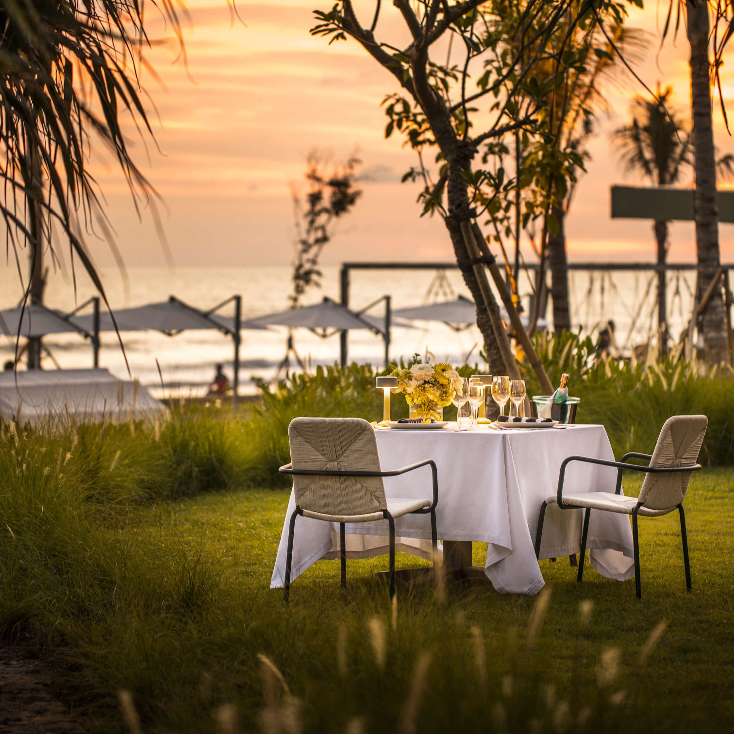 A Table Set With Chairs And A White Table With A White Tablecloth And A Body Of Water