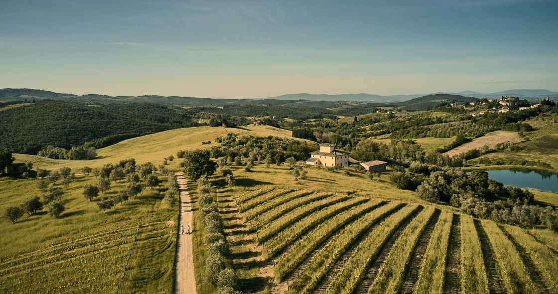 A Large Field With A House In The Distance