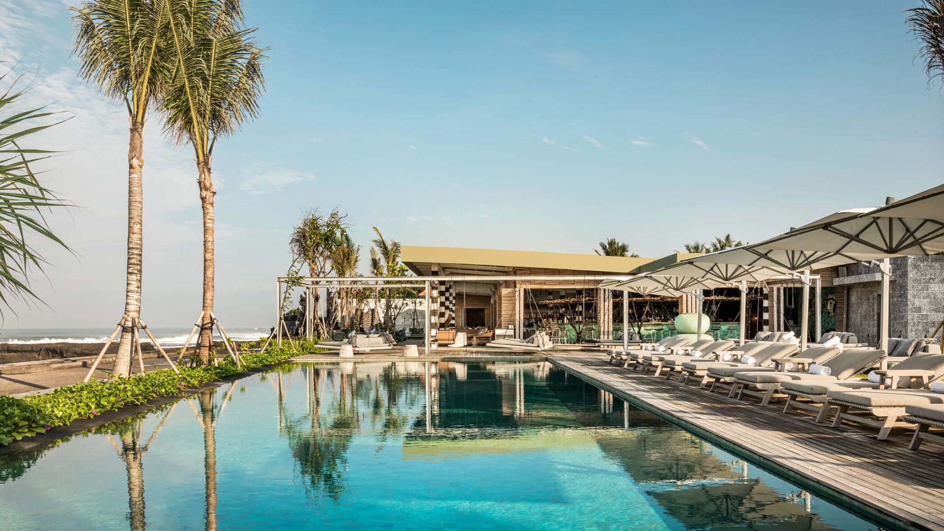A Swimming Pool With Lounge Chairs And A Building With Trees In The Background