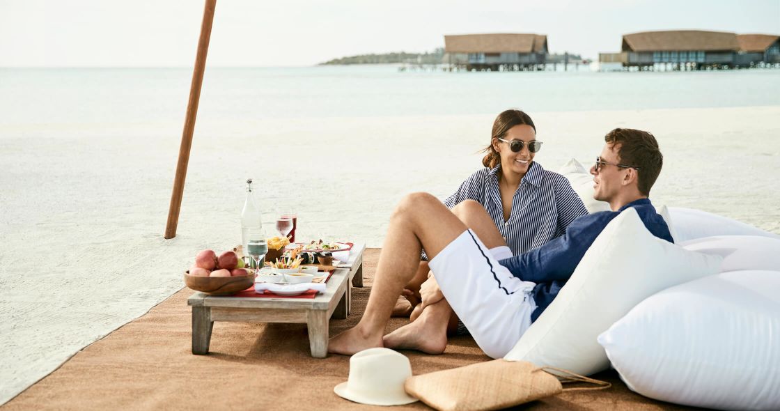 A Man And Woman Sitting On A Beach
