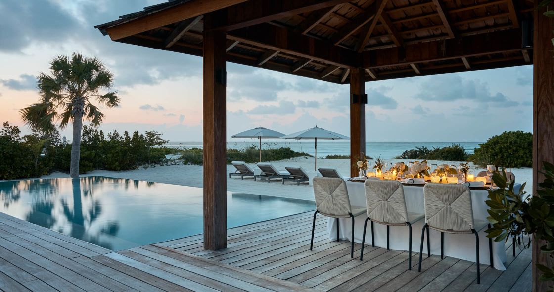 A Deck With Chairs And Umbrellas By A Pool