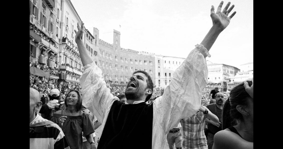 A Man With His Arms Raised In The Air In Front Of A Crowd