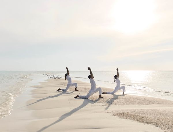 A Group Of People Jumping On A Beach