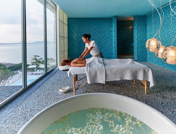 A Man And Woman Sitting On A Bed In A Room With A Large Window And A Large Globe