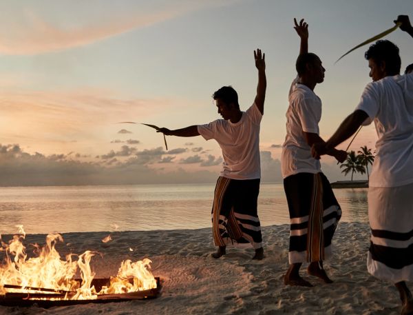 A Group Of People Standing Around A Fire