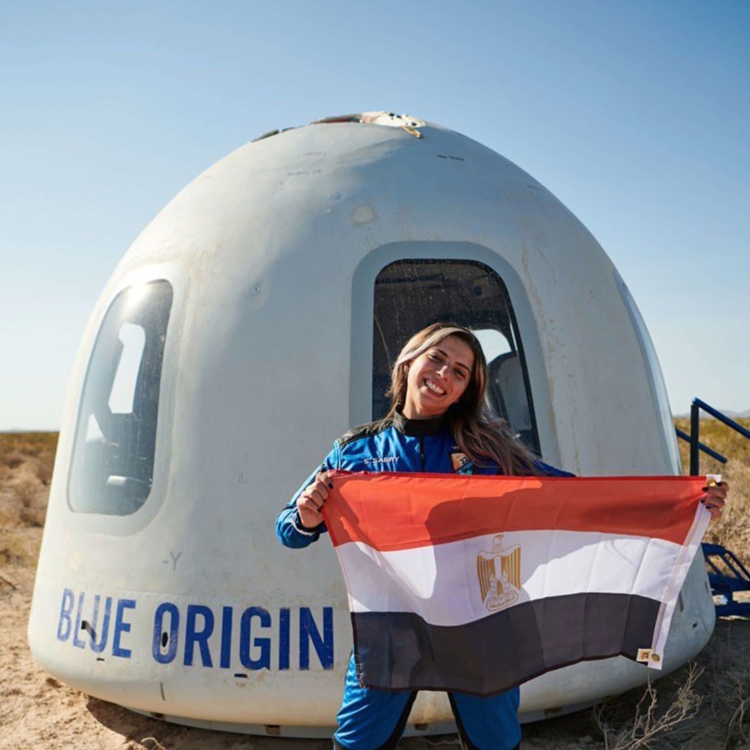 A Man Standing In A Large White And Blue Capsule