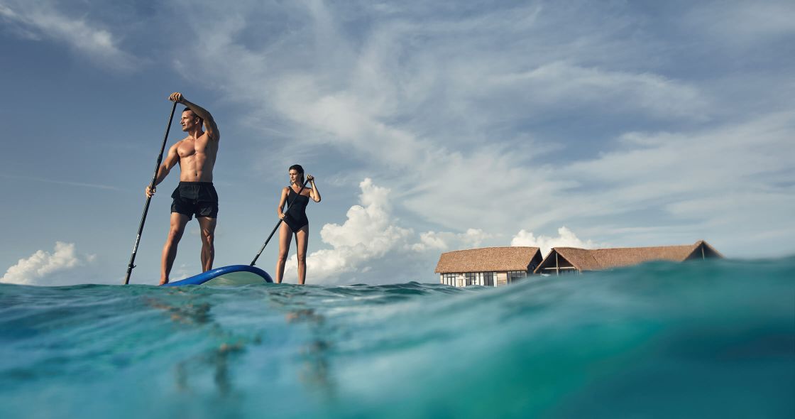 A Couple Of People Paddle Surfing