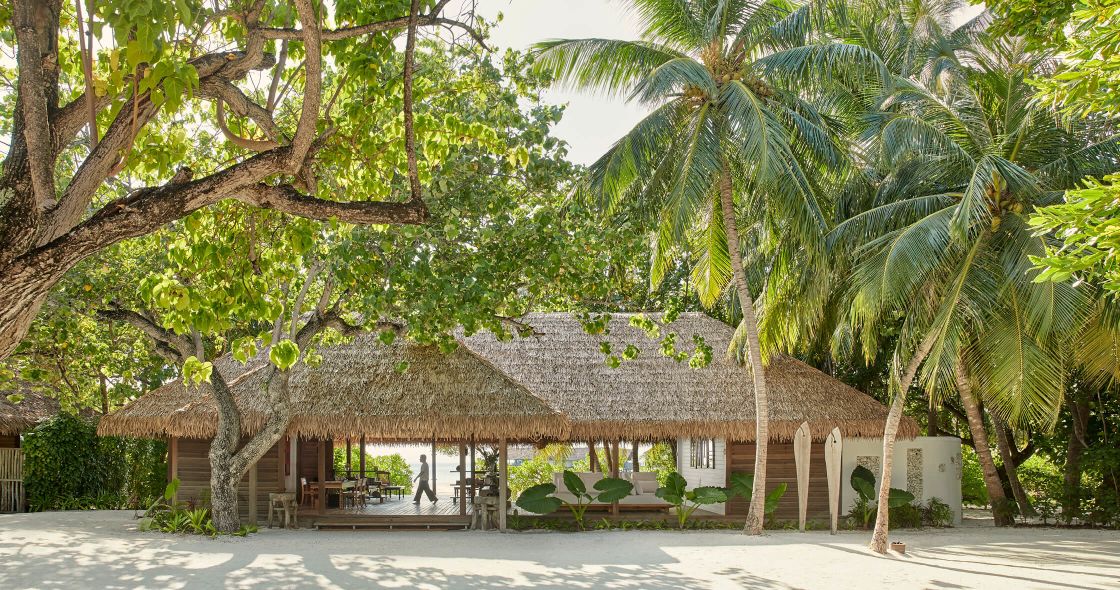 A Couple Of Huts With Palm Trees